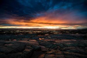 a sunset over a rocky field with a cloudy sky at Chalet Le Pointu - St-Lawrence River View in Rivière-du-Loup