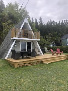 a house with a deck with chairs and a balcony at Chalet Le Pointu - St-Lawrence River View in Rivière-du-Loup