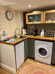 a kitchen with a washing machine and a clock on the wall at The Grannery in Wadhurst