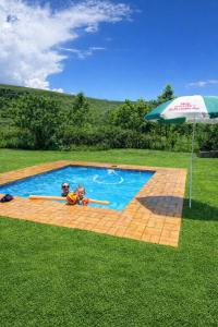 a couple of people in a swimming pool with an umbrella at Plain Champagne Guest Farm, Champagne Valley in Winterton