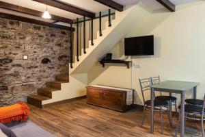 a living room with a table and a tv and stairs at Villa Rústica - Casa da Lurdes in Ribeira Brava