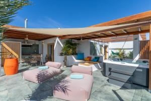 a patio with pink cushioned chairs and a kitchen and a house at El Alcaidón in Tías