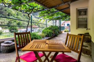 a wooden table and two chairs on a patio at Villa Rústica - Casa da Lurdes in Ribeira Brava