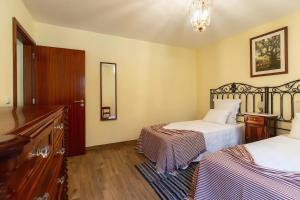 a hotel room with two beds and a dresser at Villa Rústica - Casa da Lurdes in Ribeira Brava
