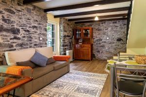 a living room with a couch and a stone wall at Villa Rústica - Casa da Lurdes in Ribeira Brava +10 photos