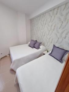 two beds in a room with white walls and purple pillows at Apartamento Rincón La Ballena in Rota +4 photos