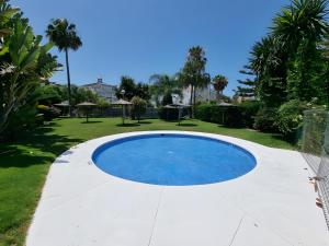 a swimming pool in a yard with palm trees at Apartamento Rincón La Ballena in Rota