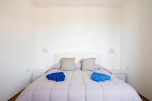 a white bed with two blue pillows on it at Casa Jerzu S'essia de su santu in Jerzu