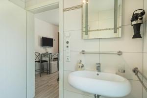 a bathroom with a white sink and a television at Apartment mit Kaffeeküche für Zwei in Meersburg +13 photos