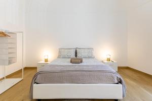 a white bedroom with a large bed and two night stands at Vico21 nel centro di Modica in Modica