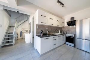 a kitchen with white cabinets and a stainless steel refrigerator at Kate House in Ágios Matthaíos +18 photos
