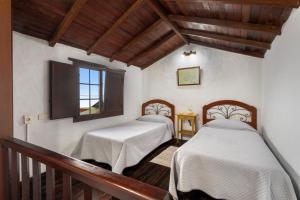 two beds in a room with wooden ceilings at Tesbabo Rural - Camelia in Mocanal