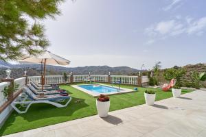 a backyard with a swimming pool and a lawn with chairs and an umbrella at Entre montañas in Árchez
