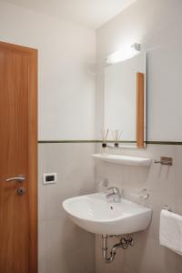 a white bathroom with a sink and a mirror at Ciasa Willy App Sas La Crusc in La Villa +21 photos