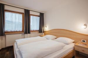 a bedroom with two white beds and two windows at Ciasa Willy App Sas La Crusc in La Villa