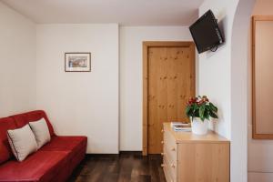 a living room with a red couch and a tv at Ciasa Willy App Sas La Crusc in La Villa
