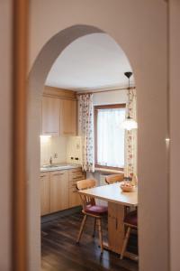 an archway in a kitchen with a table and chairs at Ciasa Willy App Sas La Crusc in La Villa