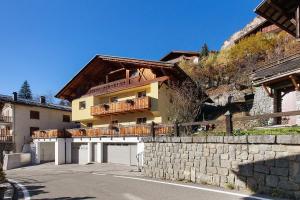 a large house with a balcony and a stone wall at Appartamenti Via Dell'Asilo in Valdidentro