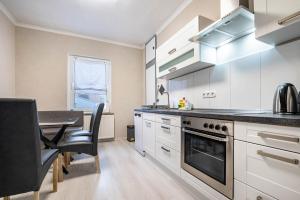 a kitchen with white cabinets and a table and a dining room at Ferienwohnung Krause Dachgeschoss in Wilhelmshaven