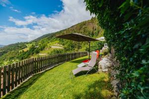 a chair and an umbrella sitting in the grass at Maso Fallmerayer - Fallmerayerhof in Bressanone