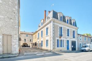 a white building with blue windows on a street at Trois Clés Apartment 1 - 1 bed in Eymet