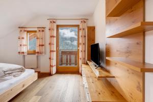 a bedroom with a bed and a tv and a window at Mair am Tinkhof in Selva dei Molini