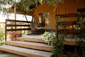 a porch with a swing and flowers on it at Glamping Alcantara in Motta Camastra