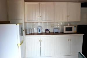 a kitchen with white cabinets and a microwave at De Kothuize 16 in Graaff-Reinet +1 photo