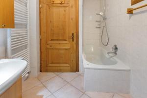 a bathroom with a bath tub and a wooden door at Chalet di Mont in Valfurva +20 photos