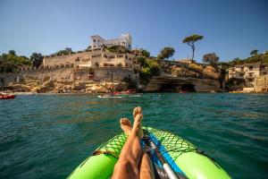 a person on a boat in the water with their legs up at Baia delle Rocce Verdi Resort in Naples +10 photos