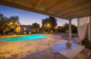 a patio with a table and chairs and a swimming pool at Villa Dina in Nardò