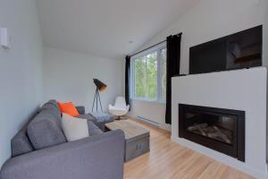 a living room with a couch and a fireplace at La Relache - Nature & Relaxation - Pet Friendly in Pont-Rouge