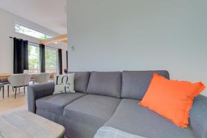 a living room with a gray couch with an orange pillow at La Relache - Nature & Relaxation - Pet Friendly in Pont-Rouge +39 photos