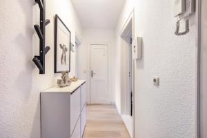 a hallway with white walls and a white cabinet and a door at Wohnung Horsti in Timmendorfer Strand +15 photos