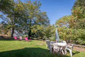 a table with chairs and an umbrella on a lawn at Gite Dans Grange Foraine - Baou in Artalens-Souin