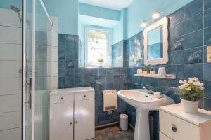 a blue tiled bathroom with a sink and a shower at Gite Dans Grange Foraine - Baou in Artalens-Souin +13 photos
