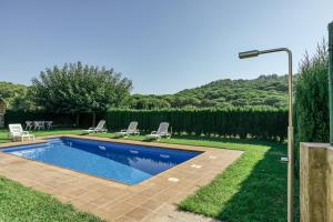 a swimming pool in a yard with chairs and a lamp at Mas Cases in Girona