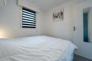 a white bedroom with a bed and a window at Le Sailing,parking, proche plage in Arzon