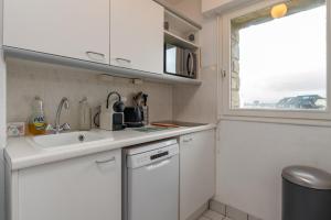 a kitchen with white cabinets and a sink and a window at Le Sailing,parking, proche plage in Arzon