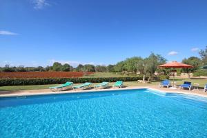 a swimming pool with chairs and an umbrella at S'hort des Cura in Islas Baleares