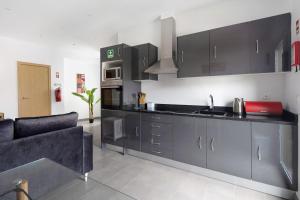 a kitchen with black cabinets and a couch at Capelas Pdl Apartment in Capelas