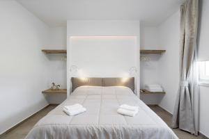 a bedroom with a white bed with two towels on it at Appartamenti Dama 1 in Bardolino