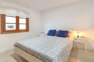 a bedroom with a bed with blue pillows and a window at Vela in Arrecife