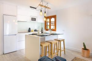 a kitchen with white cabinets and a kitchen island with stools at Vela in Arrecife