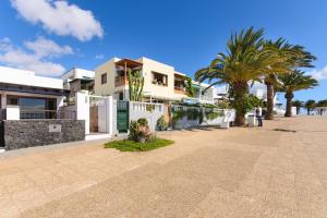 a street in front of a house with palm trees at Vela in Arrecife