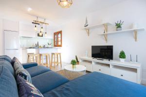 a living room with a blue couch and a kitchen at Vela in Arrecife