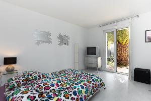 a white bedroom with a bed and a tv at Maison De Vacances 8pers Seignosse in Seignosse
