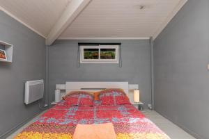 a bedroom with a bed with a red comforter and a window at Maison De Vacances 8pers Seignosse in Seignosse +16 photos