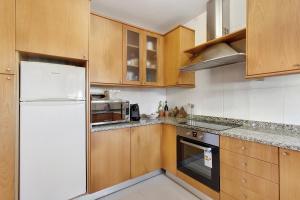 a kitchen with a white refrigerator and wooden cabinets at Dunas Das Marinhas in Marinhas