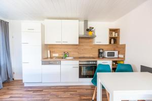 a kitchen with white cabinets and a table with blue chairs at Ferienwohnung Rambold Sonnenterrasse in Garmisch-Partenkirchen +19 photos